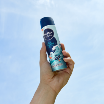 Męski antyperspirant NIVEA MEN Cool Marine w błękitnym sprayu, 72h ochrona, z morskim wzorem, w dłoni na tle nieba.