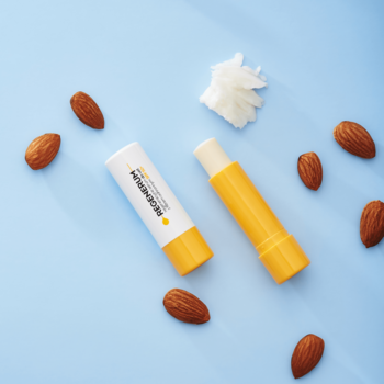 Dwa żółte serum do ust Regenerum SPF 50+, jedno otwarte, widok z góry na niebieskim tle z migdałami i masłem shea.
