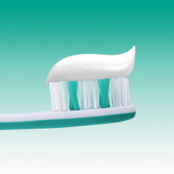 Biała pasta do zębów Elmex Sensitive Whitening na zielono-białej szczoteczce, zbliżenie, jasne tło.