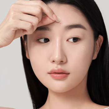 Kobieta aplikuje półprzezroczysty plaster na niedoskonałości na czoło. Niewidoczne plastry na trądzik.