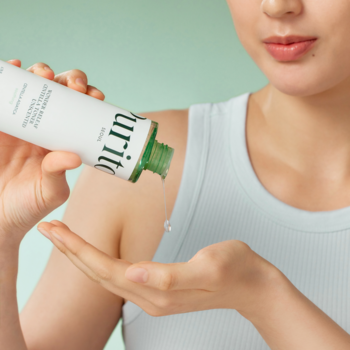 Centella Unscented Serum, biała butelka, kobieta wlewa bezzapachowe serum na dłoń, tło zielone, zbliżenie.