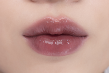 Usta z błyszczykiem Rom&nd Juicy Lasting Tint nr 25. Intensywny różowo-brązowy kolor i lustrzany, mokry połysk.