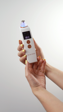 Białe urządzenie B-Derma PRO do mikrodermabrazji diamentowej w dłoniach, z ekranem LCD i niebieskim światłem.