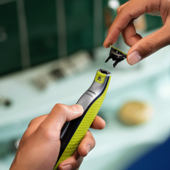 Ręce mocują ostrze 360 do maszynki Philips OneBlade w zielono-szarym kolorze, widok z bliska na wymianę.