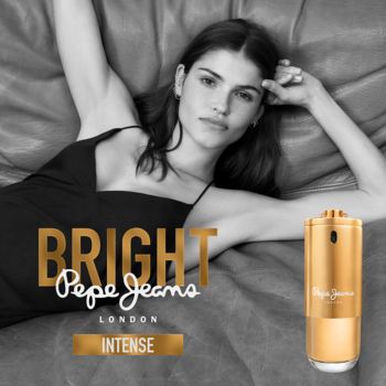 Złota butelka Pepe Jeans London Bright Intense, woda perfumowana, obok leżącej kobiety.