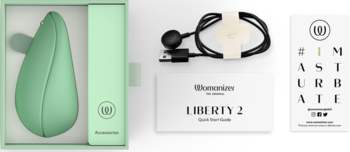 Zestaw Womanizer Liberty 2: miętowy stymulator Pleasure Air w otwartym etui z akcesoriami i kablem USB.