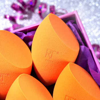 Zestaw 4 pomarańczowych gąbeczek Real Techniques Miracle Complexion Sponge w fioletowym pudełku, widok z góry.