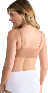 Widok z tyłu: kobieta w beżowej braletce Sloggi Zero Microfibre 2.0. Gładka, bezszwowa tkanina i regulowane ramiączka.