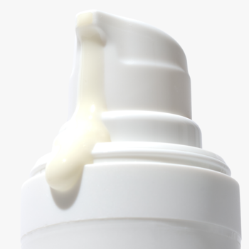 Zbliżenie białej butelki kojącego serum z witaminą C, z kroplą produktu wydobywającą się z pompki.