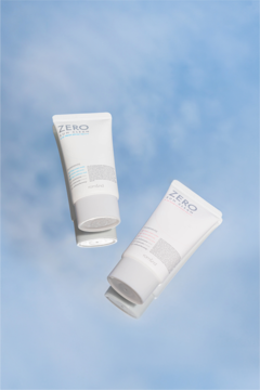 Dwa tonujące kremy przeciwsłoneczne Zero Sun Clean 02 SPF 50+ w białych tubkach na tle nieba.