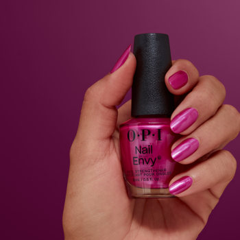 Ręka trzyma butelkę OPI Nail Envy NT229, magenta pink odżywka wzmacniająca na pomalowanych paznokciach.