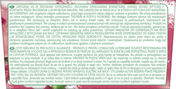 Zbliżenie na białą etykietę produktu Air Wick Essential Oils z czarnym tekstem, na tle różowych malin.