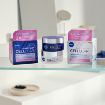 Dwa słoiczki i pudełka kremów NIVEA HYALURON CELLULAR FILLER dzień/noc na szklanej półce.