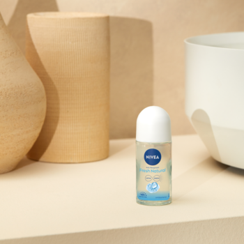 NIVEA Fresh Natural roll-on antyperspirant 50ml, przezroczysta butelka z niebieską etykietą, białą nakrętką na beżowym tle.