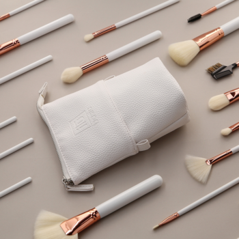 Ilū Basic Set: zestaw wegańskich pędzli z białymi rączkami, różowym złotem i białym etui, na beżowym tle.