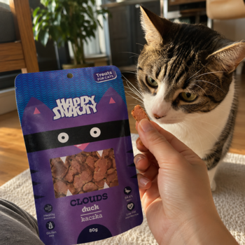 Kot patrzy na przysmak z kaczki Happy Snacky Clouds; obok fioletowe opakowanie miękkich filetów dla kotów.