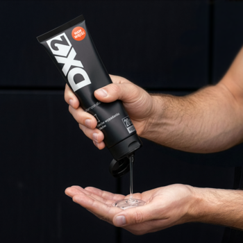 Mężczyzna wylewa przezroczysty Szampon DX2 przeciw wypadaniu włosów z czarnej tubki do otwartej dłoni.