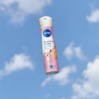 Różowy antyperspirant NIVEA Blooming Garden spray, 150ml, z kwiecistym wzorem, unosi się na błękitnym niebie.