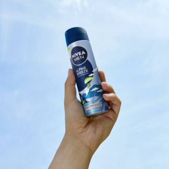 Ręka trzyma antyperspirant NIVEA MEN Alpine Breeze 72h w niebieskiej puszce na tle błękitnego nieba.