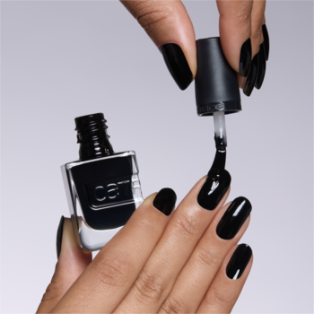 Czarny, żelowy lakier Catrice Gel Affair Black To The Roots. Dłoń maluje błyszczące paznokcie, aplikator nad butelką.