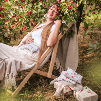 Kobieta pod wiśnią z ecru termoforem menstruacyjnym Cherry Life z pestkami wiśni na brzuchu dla ulgi.