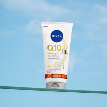 Biała tubka NIVEA Q10 Ujędrniające + Energetyzujące Serum-Balsam na szklanej półce, na tle niebieskiego nieba.