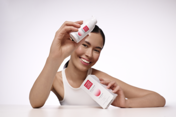 Uśmiechnięta kobieta prezentuje serum nawilżające Hada Labo Hyalu Renew w białej tubce z różowym akcentem i pudełku.