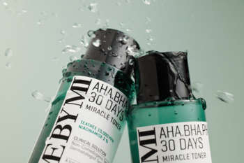Dwie butelki SOMEBYMI AHA BHA PHA 30 DAYS MIRACLE TONER z zielonym płynem, otoczone kropelkami wody.