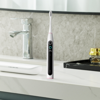 Biała szczoteczka soniczna Oclean X Lite z inteligentnym czarnym ekranem, na marmurowym blacie w łazience.