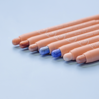 Zbliżenie na zestaw kremowych cieni w sztyfcie J.Cat Beauty Shimmie Struck, z błękitnymi i nude odcieniami, na jasnoniebieskim tle.
