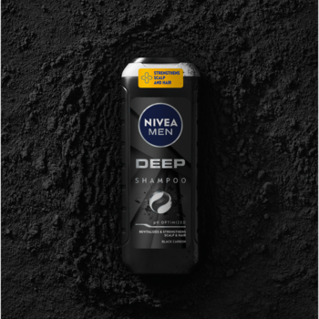 NIVEA MEN Deep Szampon z czarnym węglem, czarna butelka na tle rozsypanego węgla, widok z góry.