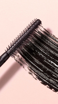 Zbliżenie na czarną szczoteczkę tuszu Collistar Infinito Mascara, która tworzy gęstą smugę na różowym tle.