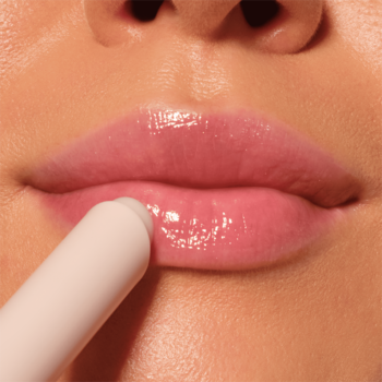 Zbliżenie na usta podczas aplikacji błyszczyka Catrice Diamond Glaze Gloss Stick, dający efekt mokrego szkła.