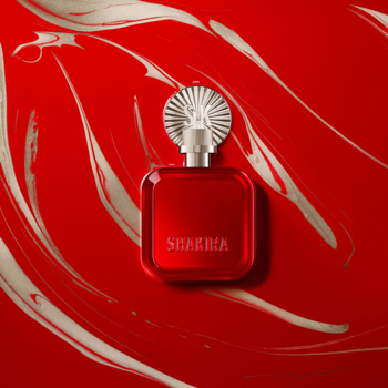 Flakon perfum Shakira ROJO EDP, rubinowo-czerwony, srebrna nakrętka, widok z góry na falistym tle.