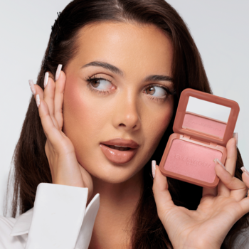 Kobieta prezentuje Baked Blush Dusty Pink. Otwarty róż do policzków w terakotowej kasetce z lusterkiem, bladoróżowy.