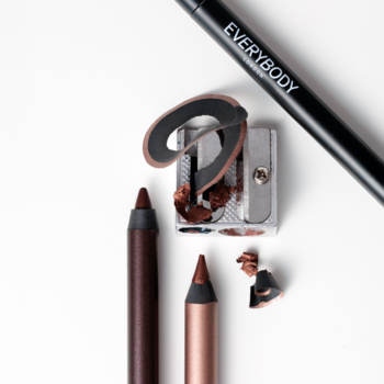 Kredki Satin Kajal Cinnamon Brown, brązowe z połyskiem, zaostrzone, na białym tle obok metalowej temperówki.