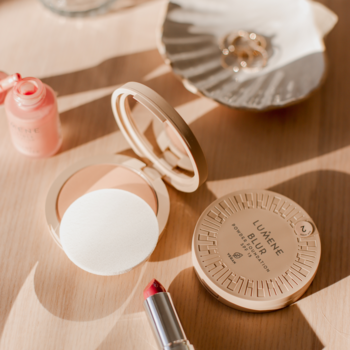 Lumene Blur puder SPF 15, odcień 0, w beżowym kompakcie, obok czerwonej szminki, na jasnym stole.