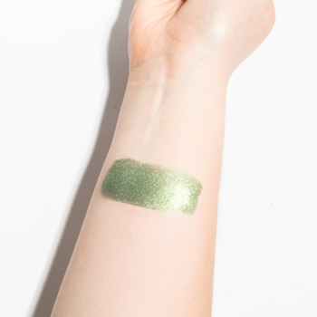 Swatch sypkiego pigmentu Shine Your Day! 152 Green Tea Frapp w pastelowej, połyskującej zieleni na przedramieniu.