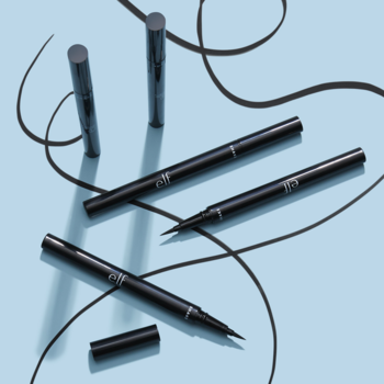 Trzy czarne, wodoodporne eyelinery e.l.f. w pisaku Jet Black, jeden z filcową końcówką, na niebieskim tle.