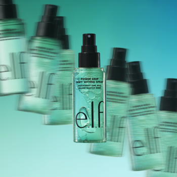 e.l.f. Power Grip Dewy Spray, dwufazowy utrwalacz makijażu. Centrowana butelka na dynamicznym tle innych butelek.