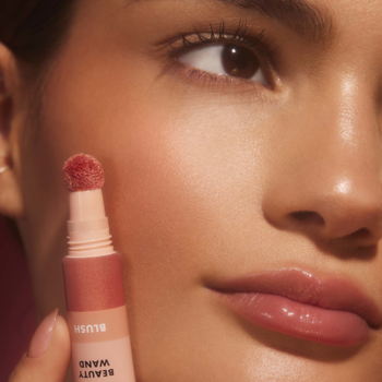 Zbliżenie na twarz z aplikatorem różu e.l.f. Halo Glow Beauty Wand, tworzącym rozświetlony efekt na policzku.