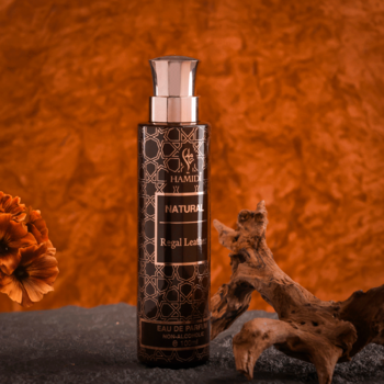Front butelki perfum HAMBBE Natural Royal Leather. Ciemna butelka z pompką, błyszczącym wzorem, na pomarańczowym tle.