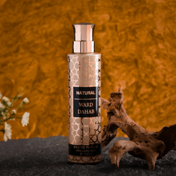 Złota butelka perfum Natural Ward Dahab z geometrycznym wzorem i miedzianym atomizerem, na ciemnym tle z drewnem.