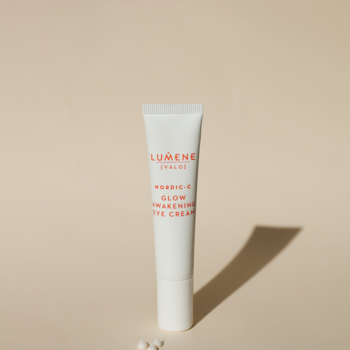 Biała tubka Lumene Nordic-C Glow Awakening Eye Cream, rozświetlający krem pod oczy, na jasnym tle z kuleczkami.