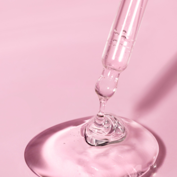 Zbliżenie na kroplę żelowej esencji kolagenowej Lumene Nordic Bloom spływającą ze szklanego zakraplacza.