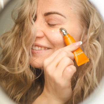 Kobieta nakłada Lumene Nordic-C Valo rozświetlające serum pod oczy z chłodzącym aplikatorem na skórę pod okiem.