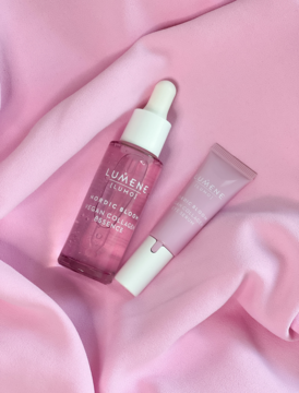 Lumene Nordic Bloom Vegan Collagen Essence (kroplomierz) i Eye Serum (tubka) na jasnoróżowej, drapowanej tkaninie.