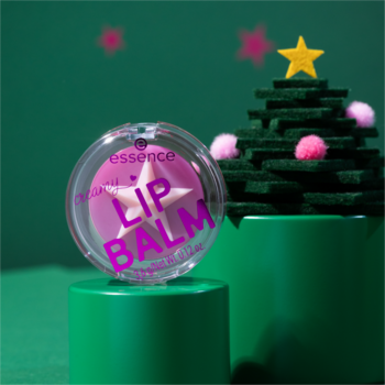 Przezroczysty compact Essence z różowym balsamem w kształcie gwiazdy, na zielonym tle z dekoracyjną choinką.