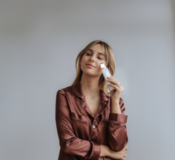 Kobieta w brązowej piżamie używa białego Beautifly Scrub Slim PRO, urządzenia do peelingu kawitacyjnego twarzy.