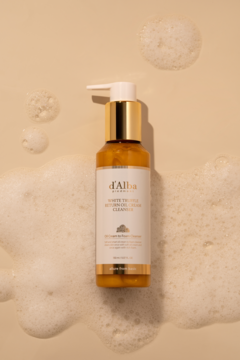 d'Alba White Truffle Return Oil Cream Cleanser, złoto-biała butelka, widok z góry, otoczona pianą na beżowym tle.